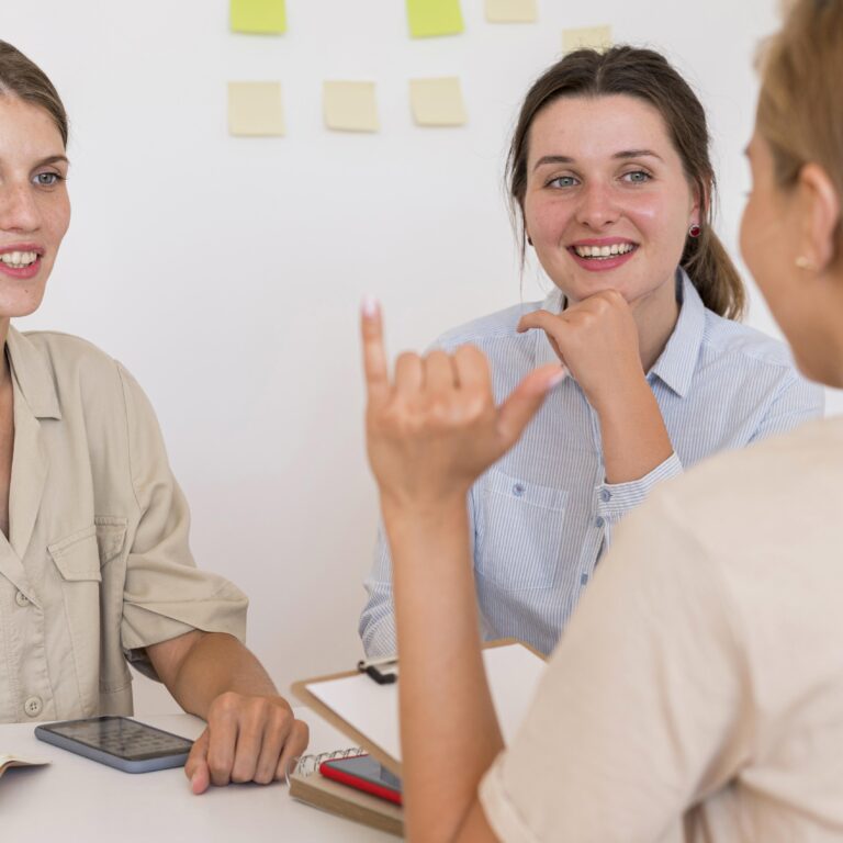 smiley-women-conversing-table-using-sign-language